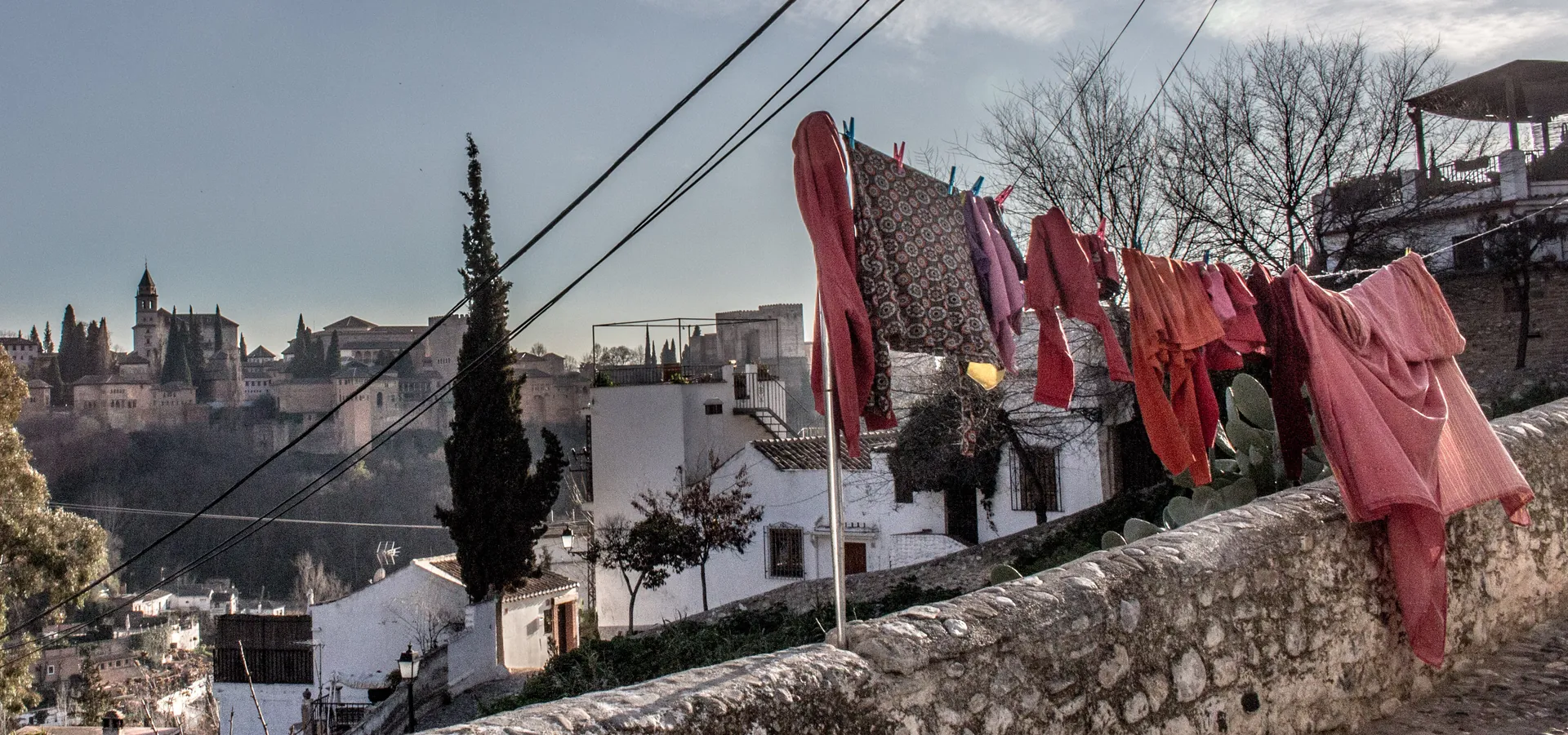Eine Wäscheleine an einer Mauer in Sacromonte mit der Alhambra auf dem Hügel dahinter; ein allgemeines Foto des Viertels