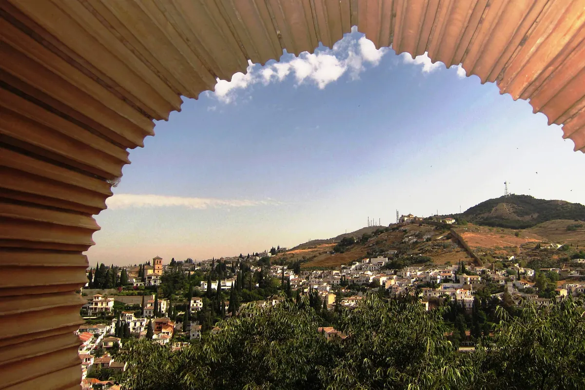Kopec Sacromonte pohledem přes zdobený oblouk v Nasridských palácích Alhambry