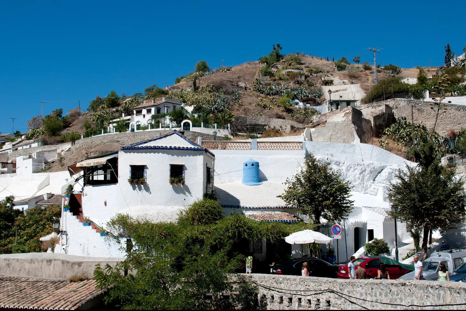 Weiß getünchte Häuser und Höhlenwohnungen, die sich den Hang von Sacromonte hinaufziehen, unter klarem Himmel; eine allgemeine Ansicht des Viertels