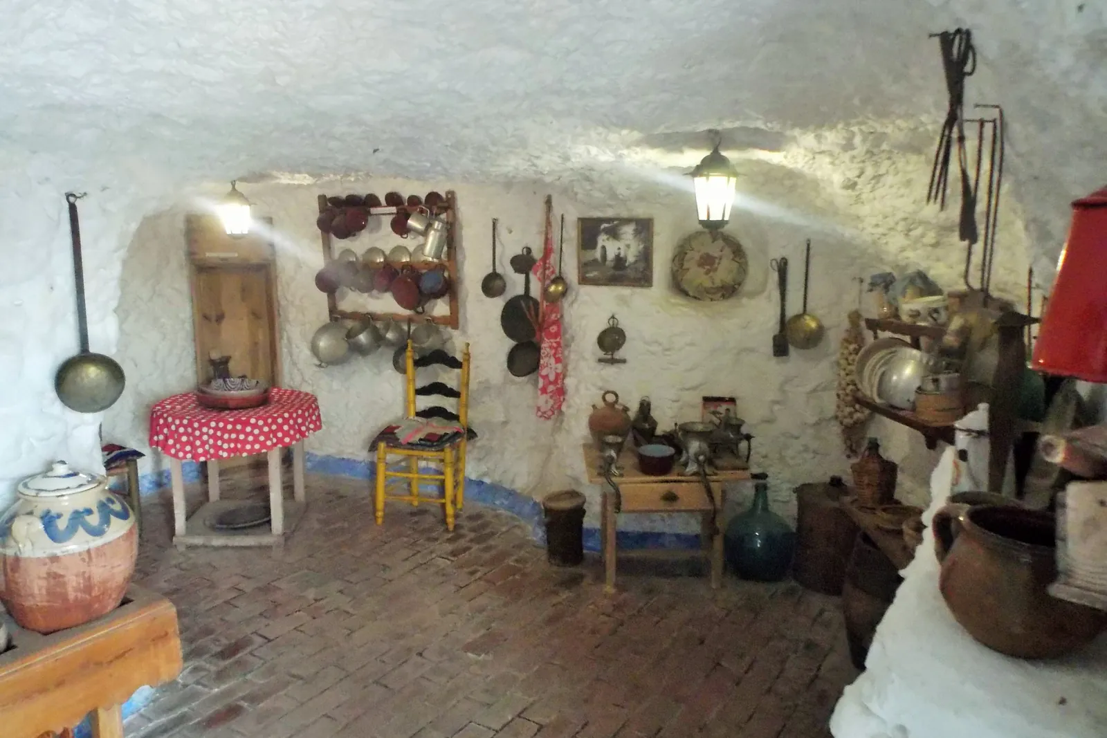 Eine nachgebaute Höhlenküche mit Töpfen, einer Lampe und einem Ziegelsteinboden im Sacromonte-Höhlenmuseum; ein allgemeines Foto, keine Schauhöhle